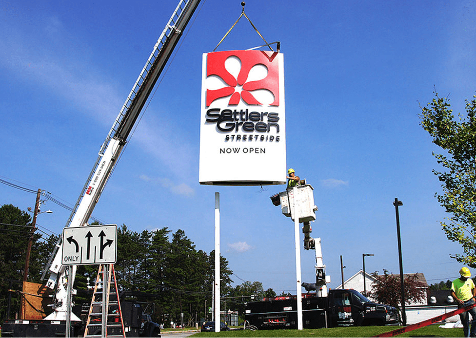 two crew members working at settlers green sign installation